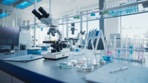 Modernes medizinisches Forschungslabor mit Mikroskop und Testtuben mit Biochemikalien am Desk