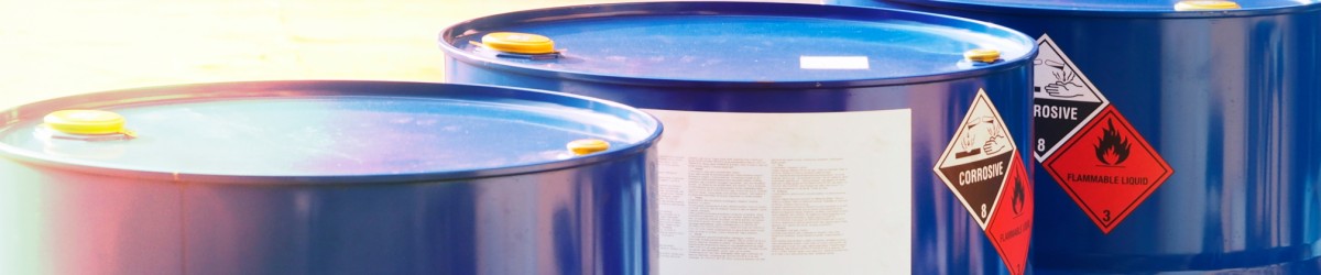 Close-up of chemical barrels with warning of corrosive substances